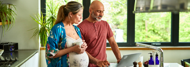 Couple expecting child review information on a computer