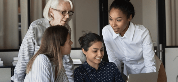 Multigenerational female employees working in a conference room together. 