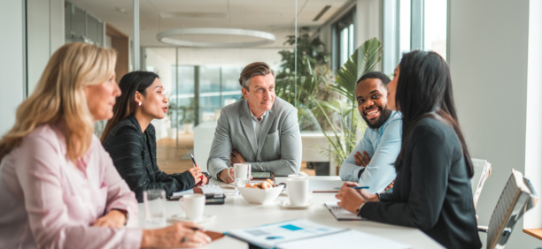 Five employees sitting around a conference table
