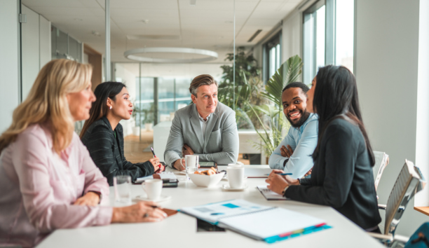 Five employees sitting around a conference table