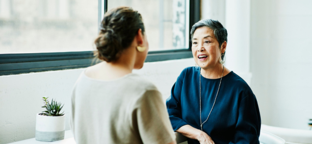 Benefits administrator meeting with an employee as they face each other.