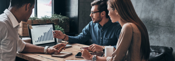 Three coworkers working together while looking at a laptop. 