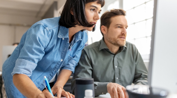 Male and female employees looking at a computer together. 