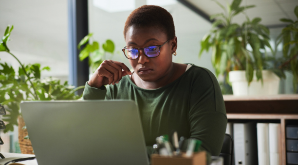 Female employee with glasses looking at laptop.