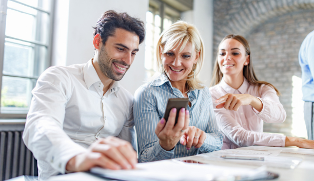 three employees looking at smartphone and smiling