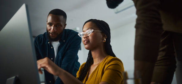 Three employees looking at a laptop.