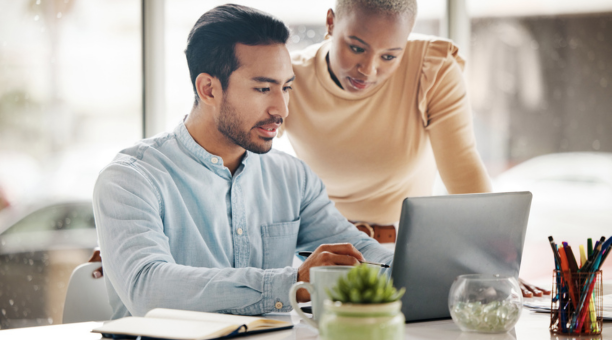 Two employees looking at a laptop together at work.